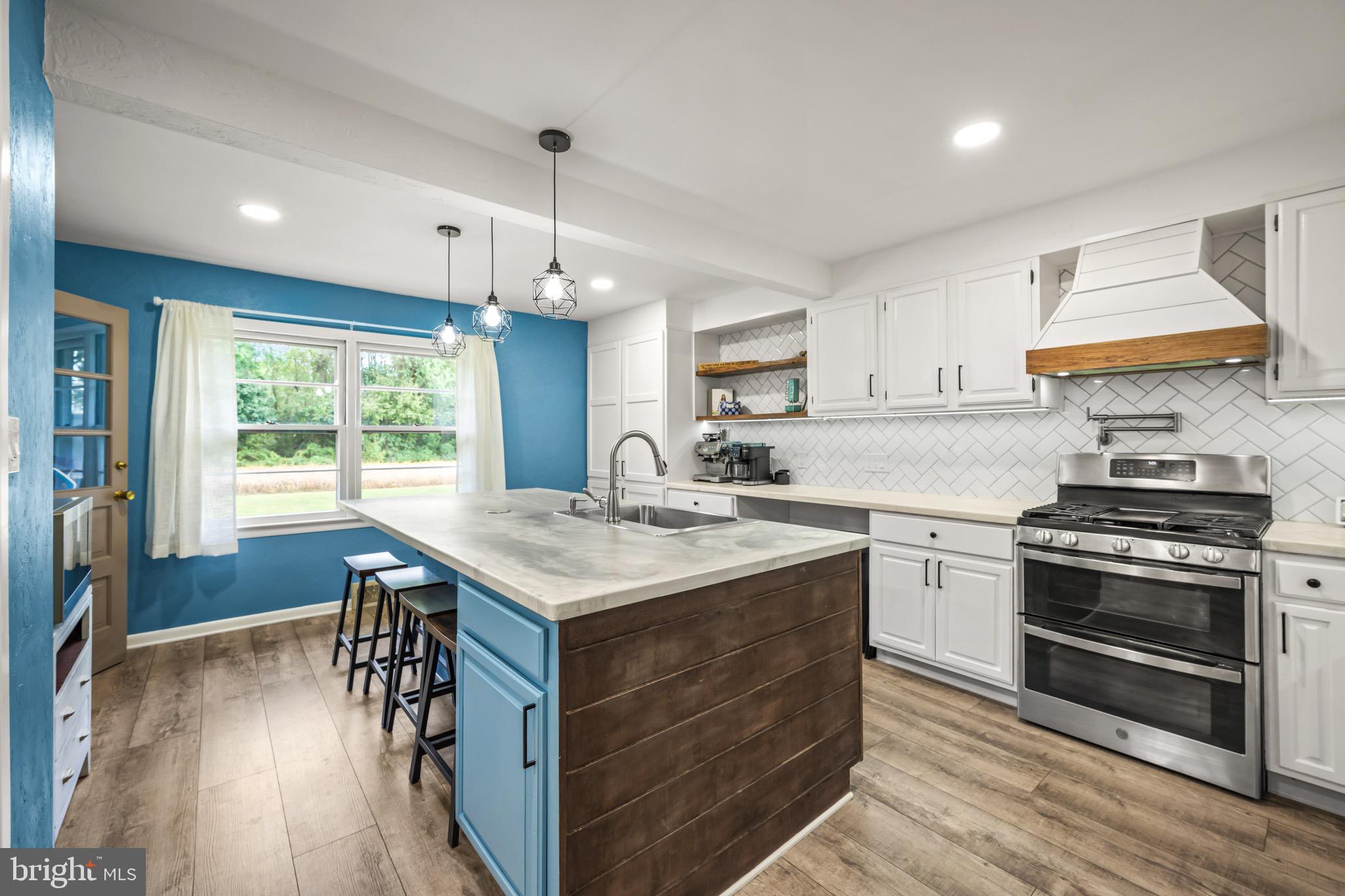 376 Griscom Drive Mannington, NJ 08079 - Photo 5 of 48 a kitchen with a stove a sink a kitchen island with wooden floor and cabinets