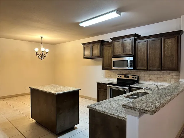 a kitchen with stainless steel appliances granite countertop a sink stove and microwave