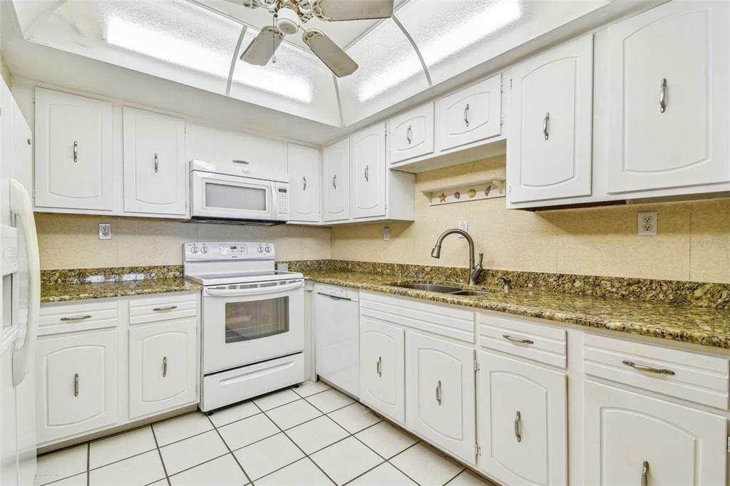 17920 Gulf Boulevard, Unit 208 Redington Shores, FL 33708 - Photo 12 of 98 a kitchen with granite countertop white cabinets and white appliances