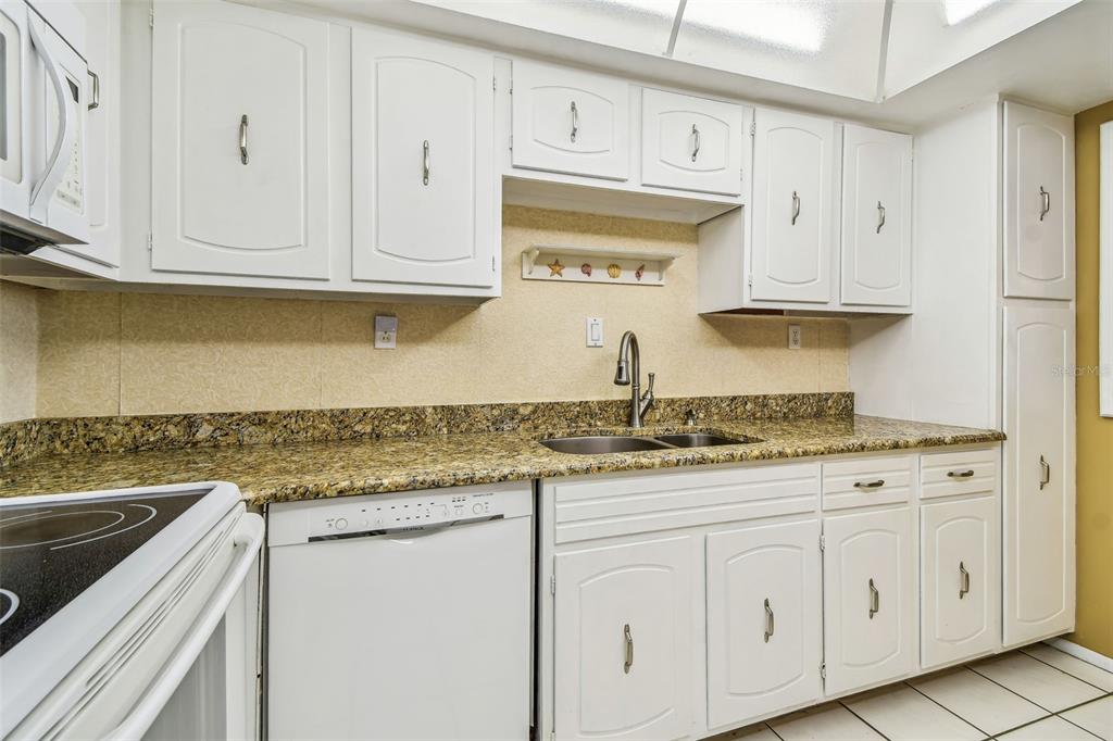 17920 Gulf Boulevard, Unit 208 Redington Shores, FL 33708 - Photo 16 of 98 a kitchen with granite countertop white cabinets and a stainless steel appliances