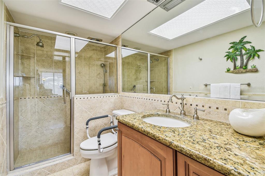 17920 Gulf Boulevard, Unit 208 Redington Shores, FL 33708 - Photo 35 of 98 a bathroom with a granite countertop sink a toilet a mirror and shower