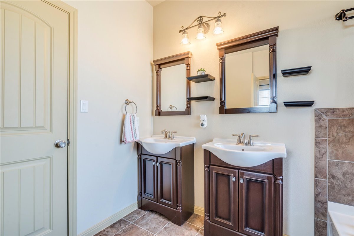 909 County Road 342 Granger, TX 76530 - Photo 20 of 37 Primary bathroom featuring two vanities, garden tub, separate shower & walk in closet