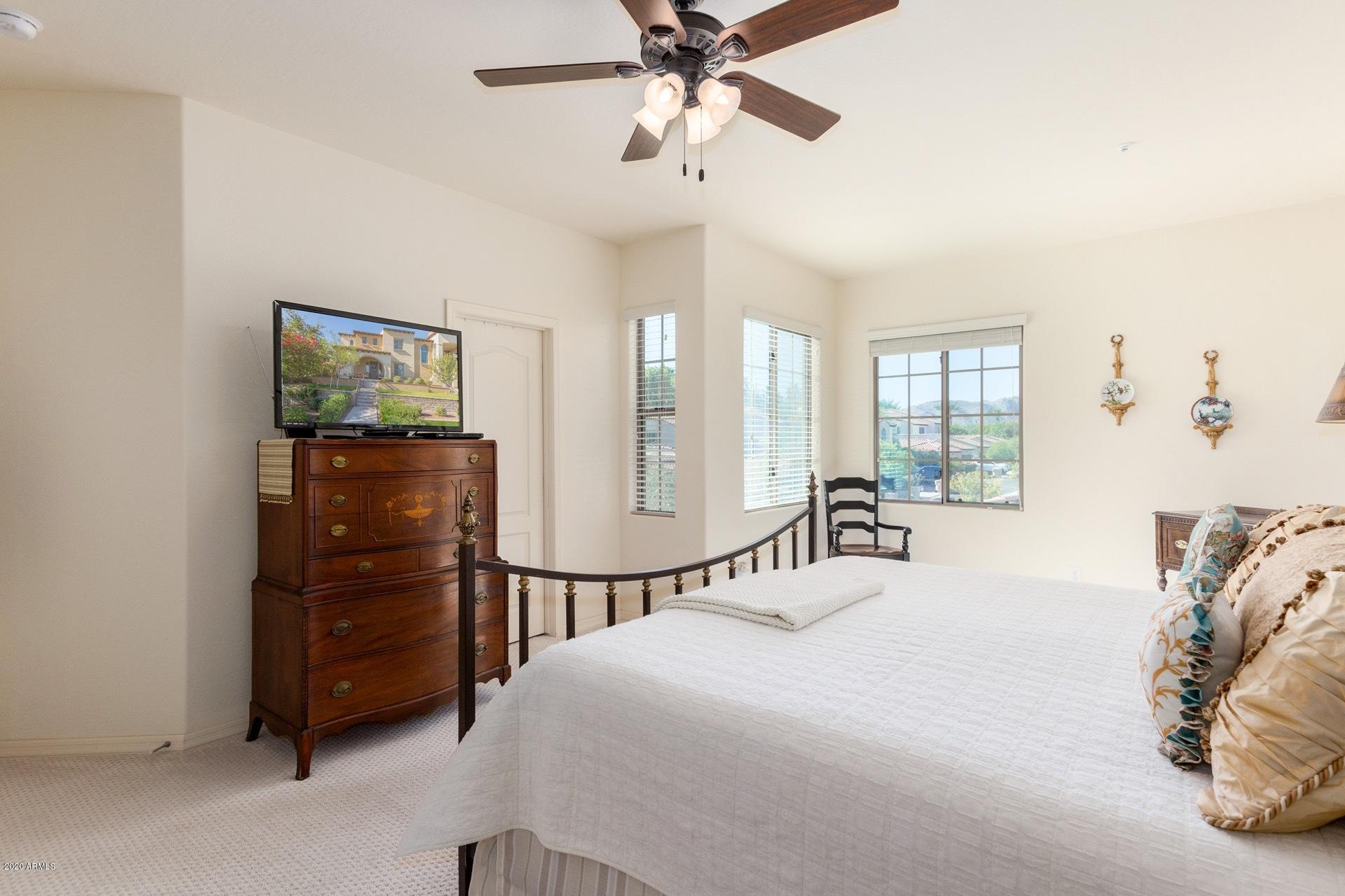 4280 North Verrado Way Buckeye, AZ 85396 - Photo 11 of 41 a bedroom with a bed a chandelier and a large mirror