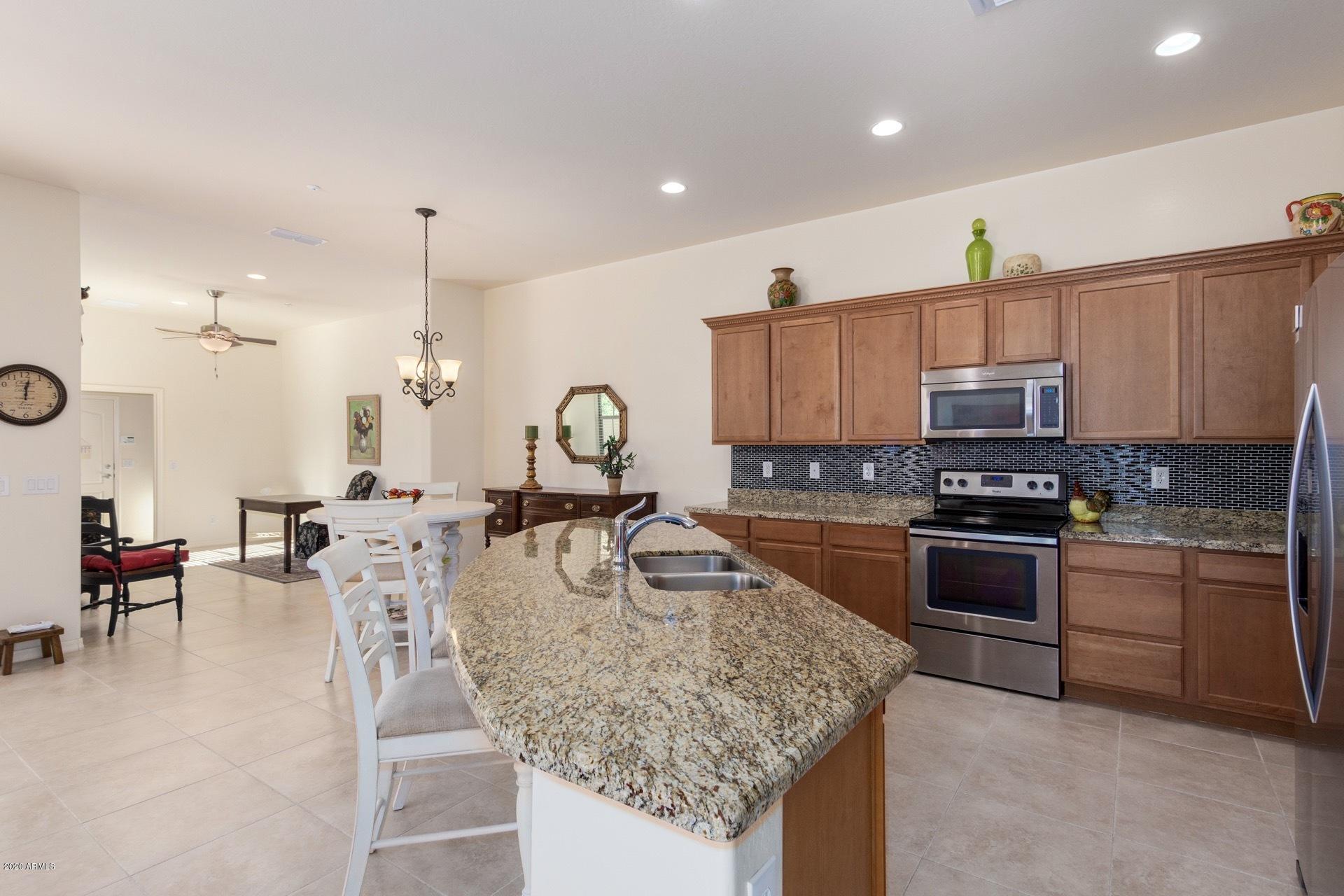 4280 North Verrado Way Buckeye, AZ 85396 - Photo 2 of 41 a kitchen with kitchen island granite countertop a stove and a sink
