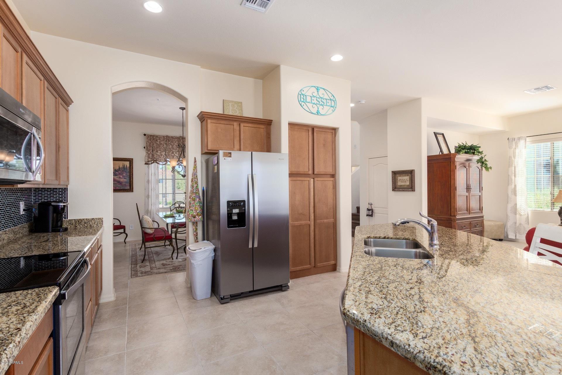 4280 North Verrado Way Buckeye, AZ 85396 - Photo 3 of 41 a kitchen with stainless steel appliances granite countertop a refrigerator a stove and a sink