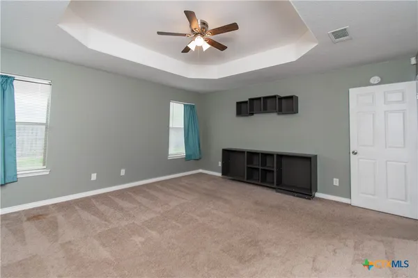 an empty room with windows and ceiling fan