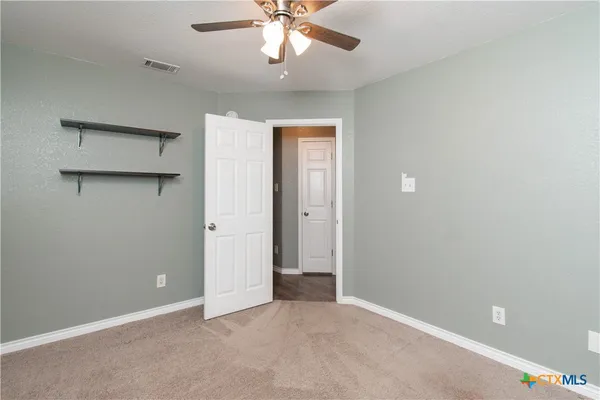 an empty room with chandelier fan and windows