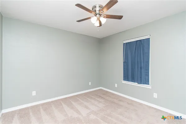 an empty room with a window and a fan