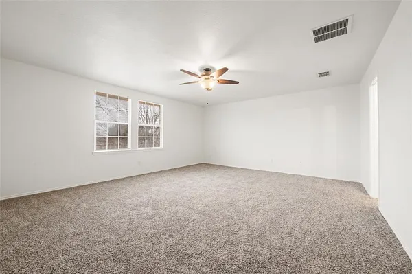 an empty room with windows and chandelier fan