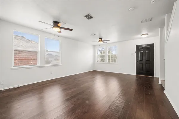 a view of an empty room with a window and wooden floor