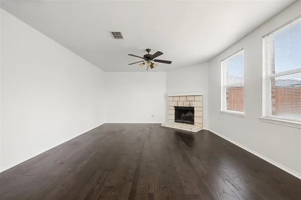 an empty room with wooden floor fireplace and windows