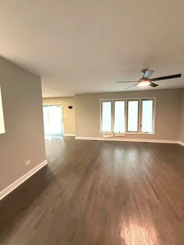 an empty room with wooden floor fireplace and windows