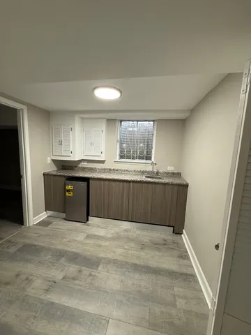 an empty room with wooden floor and kitchen view