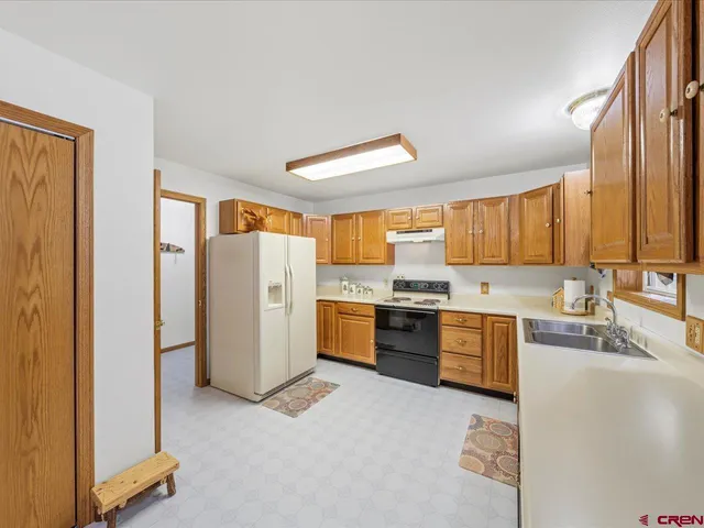 a large kitchen with a refrigerator a stove top oven a sink and dishwasher