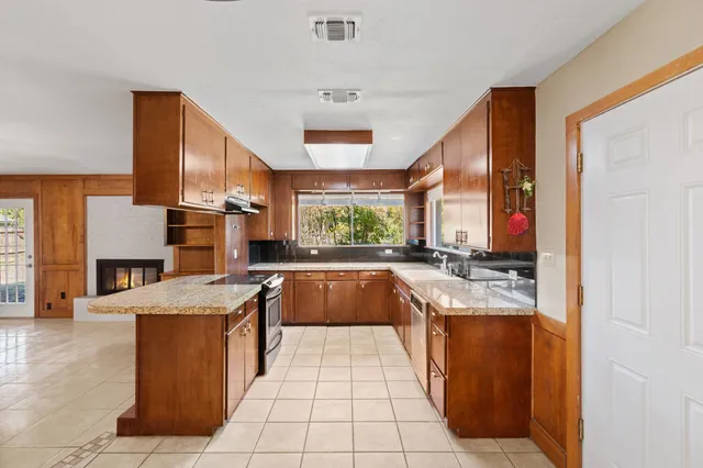 a large white kitchen with granite countertop a stove a sink and dishwasher