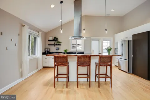 a kitchen with stainless steel appliances kitchen island granite countertop a table chairs and a refrigerator