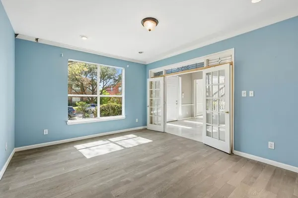 a view of an empty room with wooden floor and a window