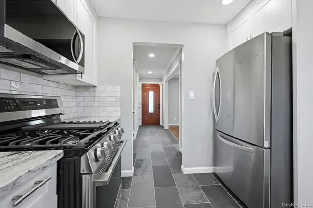 a kitchen with stainless steel appliances granite countertop a refrigerator and a stove top oven