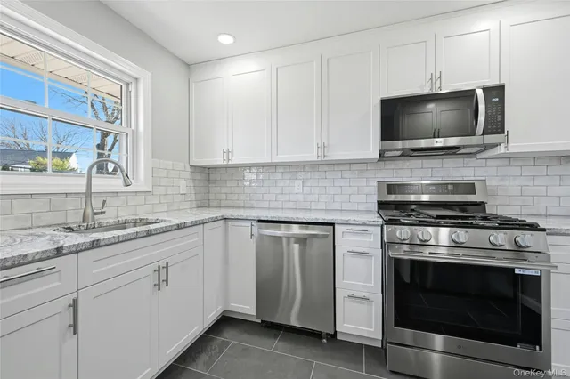 a kitchen with cabinets stainless steel appliances a sink and a window