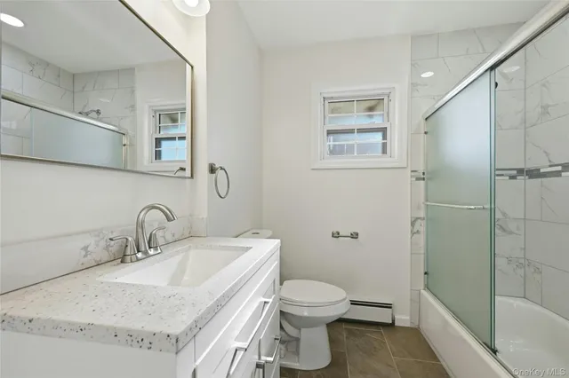 a bathroom with a granite countertop sink toilet and shower