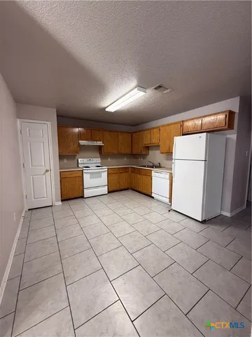 a kitchen with a refrigerator and white cabinets