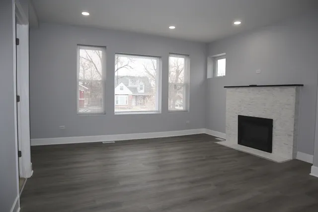 an empty room with wooden floor fireplace and windows