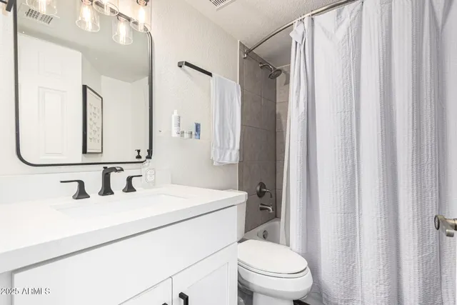 a bathroom with a granite countertop shower a toilet and a sink