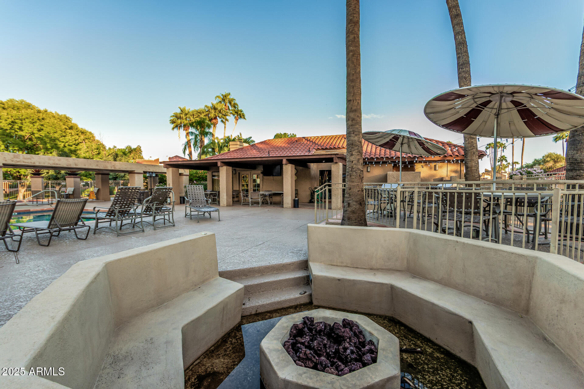 8700 East Mountain View Road, Unit 1039 Scottsdale, AZ 85258 - Photo 34 of 37 a view of a patio with couches table and chairs under an umbrella with a fire pit