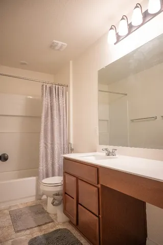 a white vase with flowers on a shelf