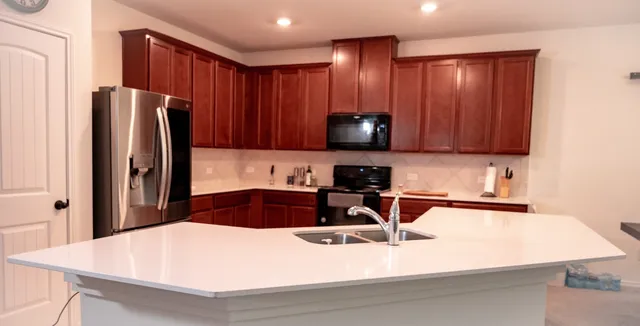 a kitchen with stainless steel appliances granite countertop a refrigerator a sink a stove a microwave and island