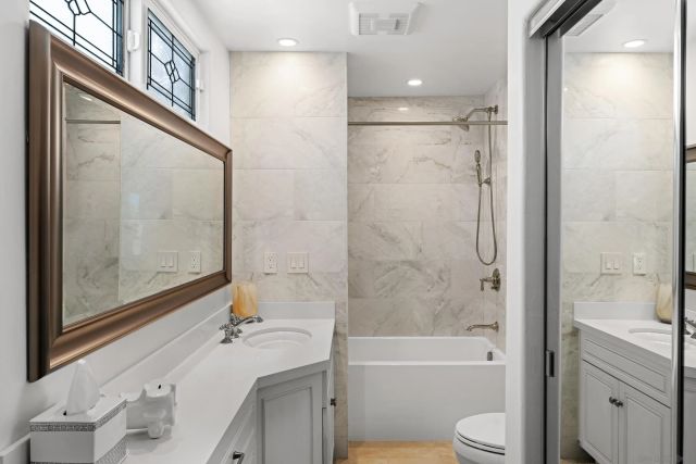 a bathroom with a bathtub shower sink vanity mirror and toilet