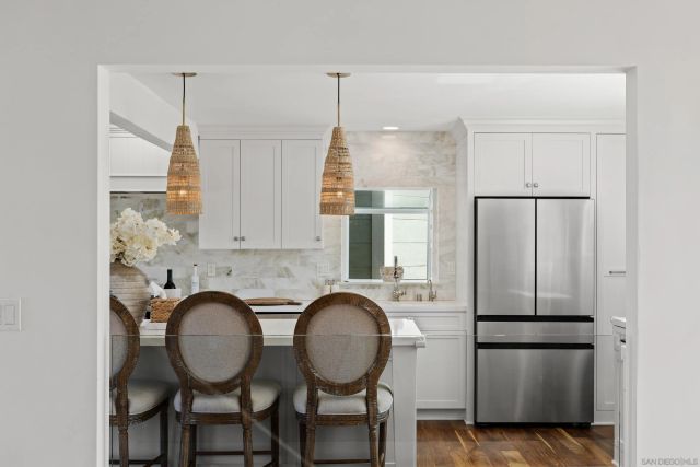 a kitchen with stainless steel appliances granite countertop a refrigerator a sink a stove and a dining table