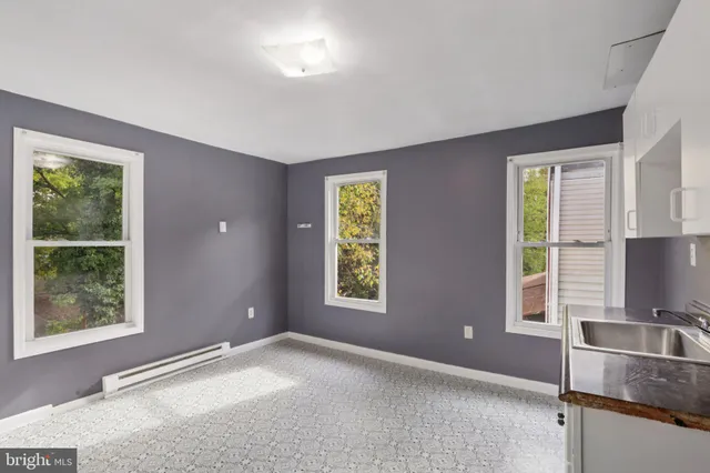 a view of an empty room with window the ceiling fan and front door