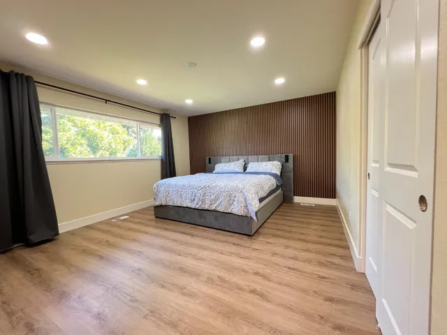 a bedroom with a large bed and a wooden floor