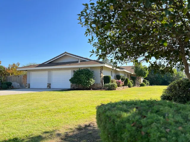 a front view of house with yard and trees in the background