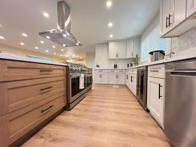 a large kitchen with stainless steel appliances kitchen island a large counter top and a stove top oven