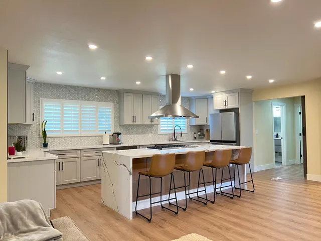 a kitchen with stainless steel appliances granite countertop a table chairs sink and cabinets