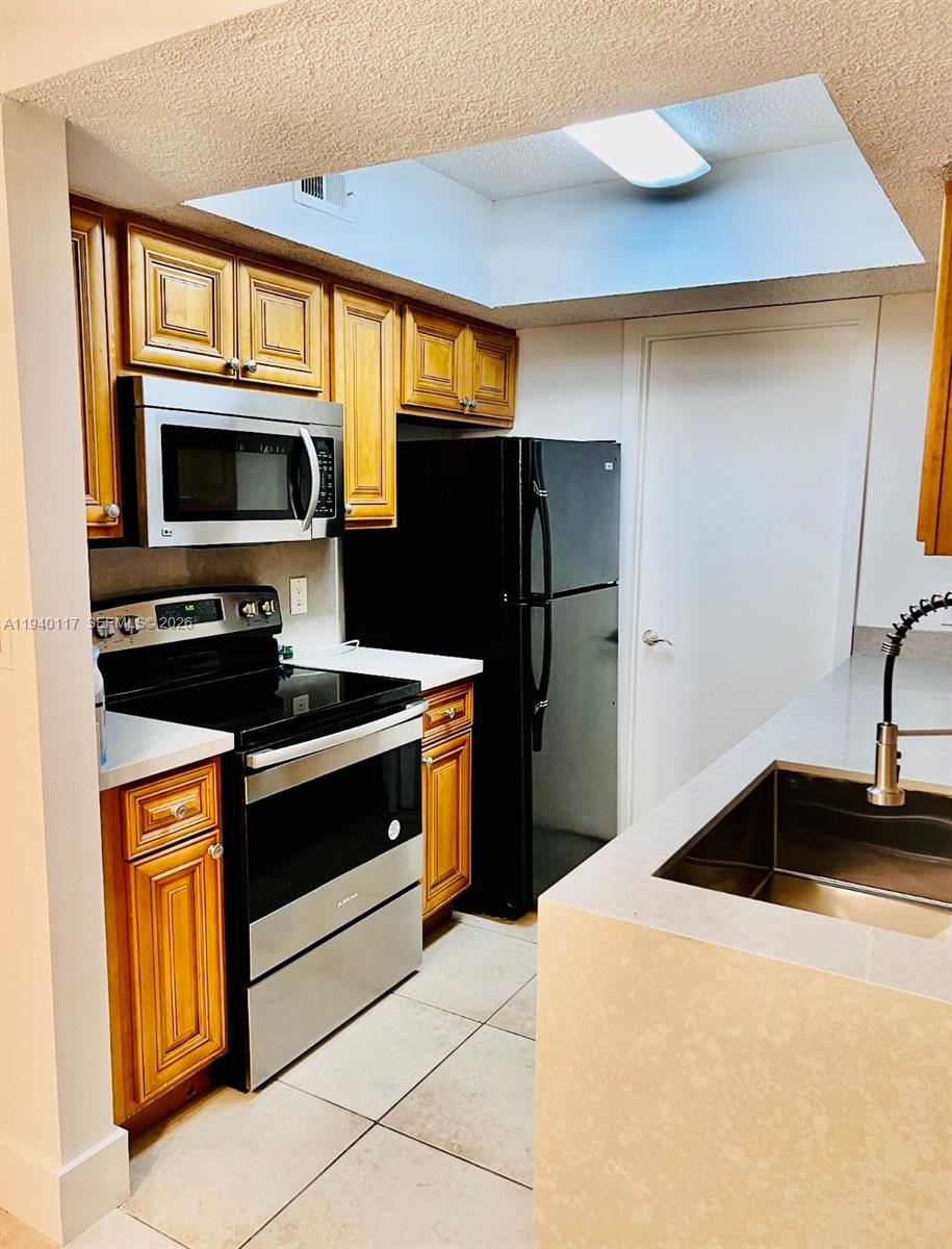 5654 Rock Island Road, Unit 214 Tamarac, FL 33319 - Photo 20 of 26 a kitchen with stainless steel appliances a stove a microwave and a refrigerator