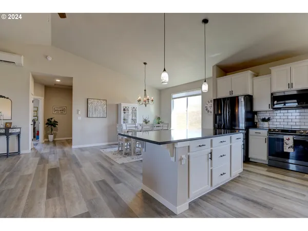 a kitchen with stainless steel appliances kitchen island granite countertop a stove top oven a sink a dining table and chairs with wooden floor