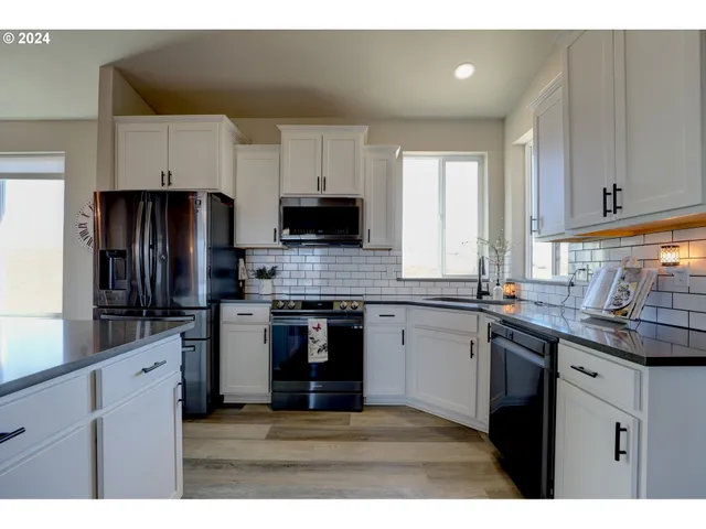 a kitchen with kitchen island granite countertop a sink dishwasher stove and refrigerator with wooden floor