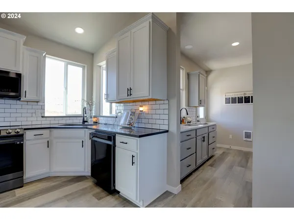 a kitchen with granite countertop a sink cabinets stainless steel appliances and a window
