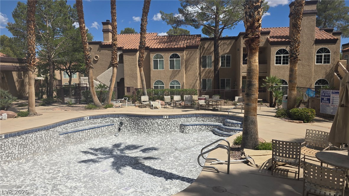 9325 West Desert Inn Road, Unit 123 Las Vegas, NV 89117 - Photo 35 of 36 A dry community pool awaits revival, surrounded by desert landscaping and a multi-story residential building with arched windows.