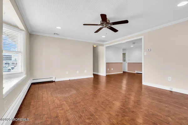 a view of empty room with wooden floor and window