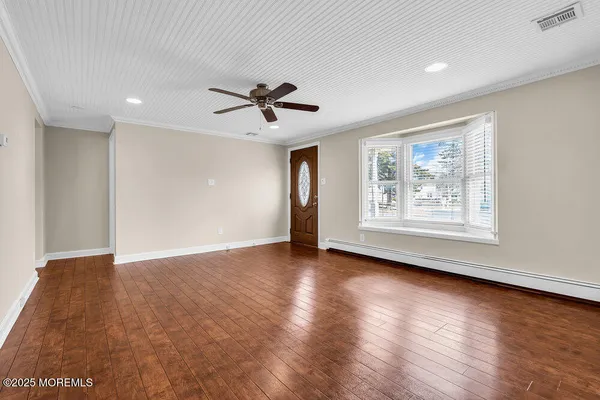 a view of an empty room with window and wooden floor