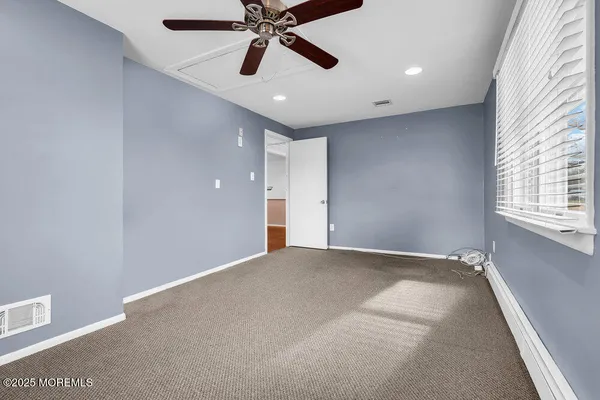 an empty room with windows and fan