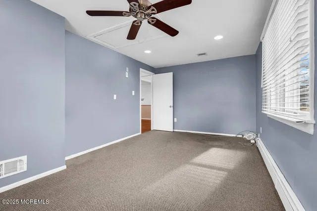 an empty room with windows and fan