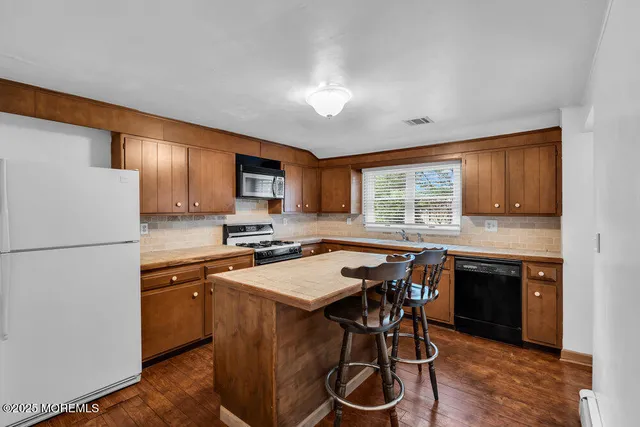 a kitchen with a sink a stove a refrigerator cabinets and wooden floor