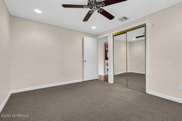 an empty room with closet and a ceiling fan