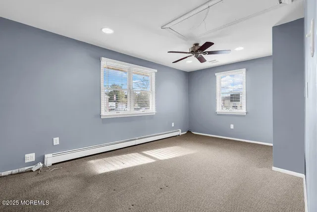 an empty room with windows and ceiling fan