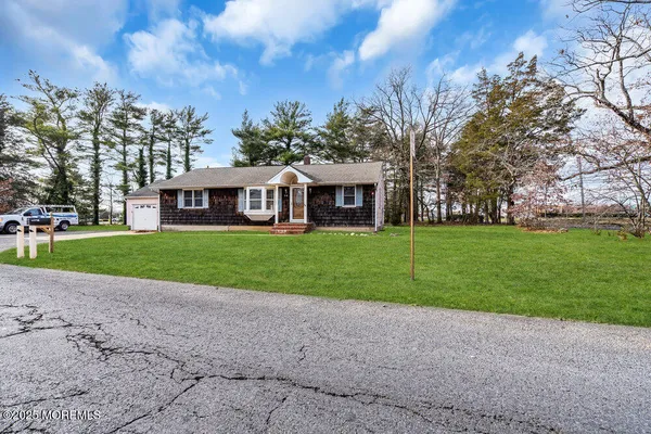 a view of house with a big yard and large trees